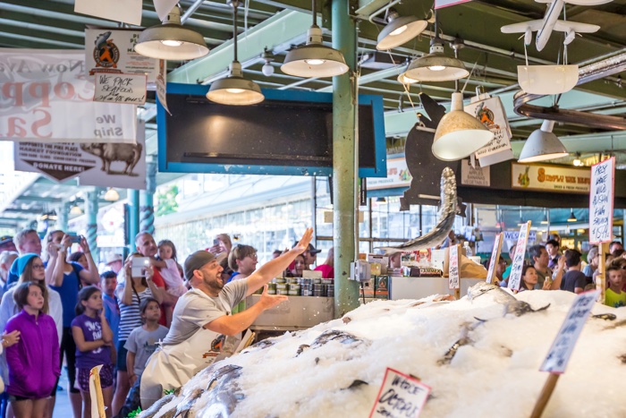 SEATTLE  JULY 5: Customers at Pike Place Fish Company wait to order fish at the famous seafood market on July 5, 2014. This market, opened in 1930, is known for their open air fish market style.