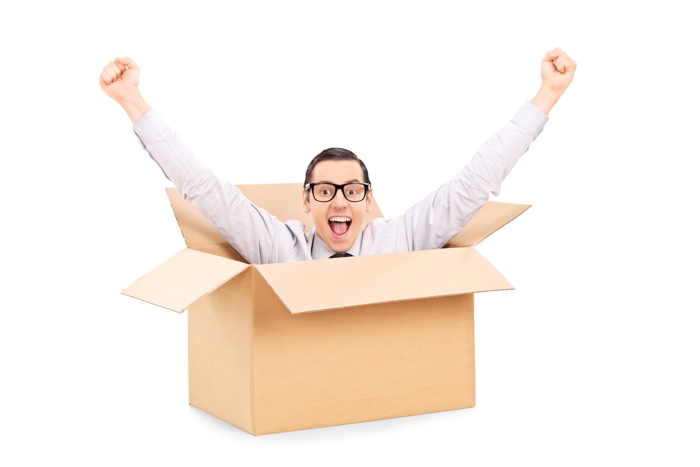 Young man gesturing happiness deep inside a box isolated on white background